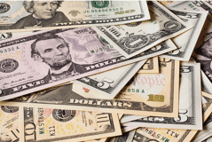 Various types of monetary bills are scattered on a flat surface on top of eachother