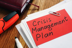 stack of papers paperclipped with note that reads Crisis Management Plan