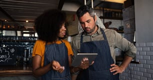 Restaurant workers view an iPad together. 