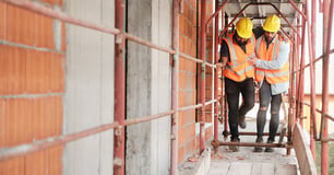 Construction worker helps a hurt fellow worker walk
