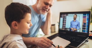 Parent helps young child with homework while attending a virtual class