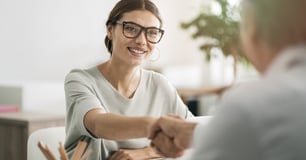 Client and business owner shake hands across a table.
