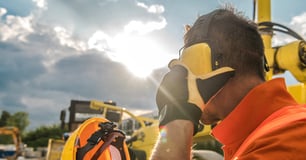 Construction worker places protective ear muffs over ears