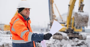 construction worker reads directions while it snows outside