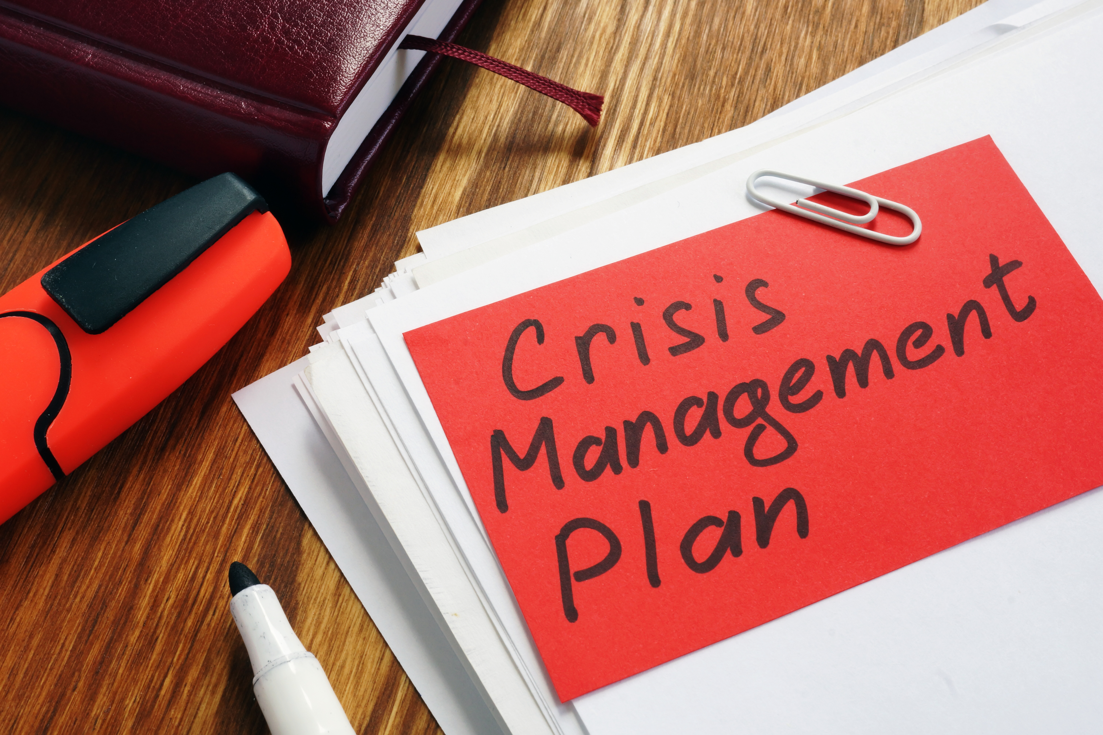 stack of papers paperclipped with note that reads Crisis Management Plan