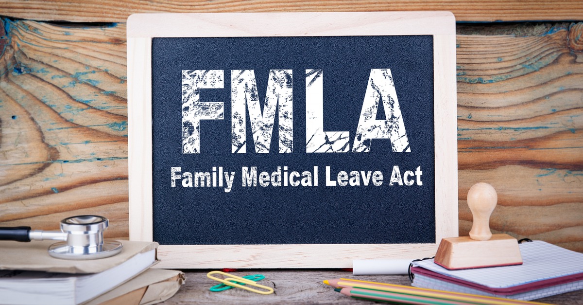 Small chalkboard with FMLA Family Medical Leave Act written on it is propped up on a desk