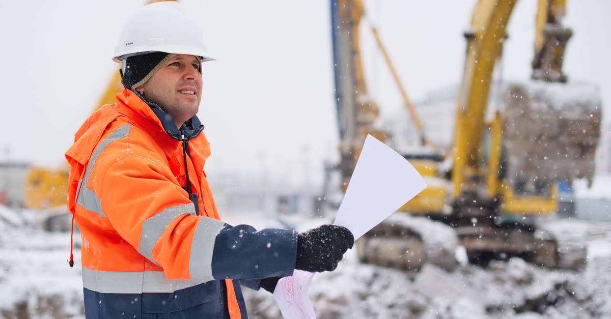 construction worker reads directions while it snows outside