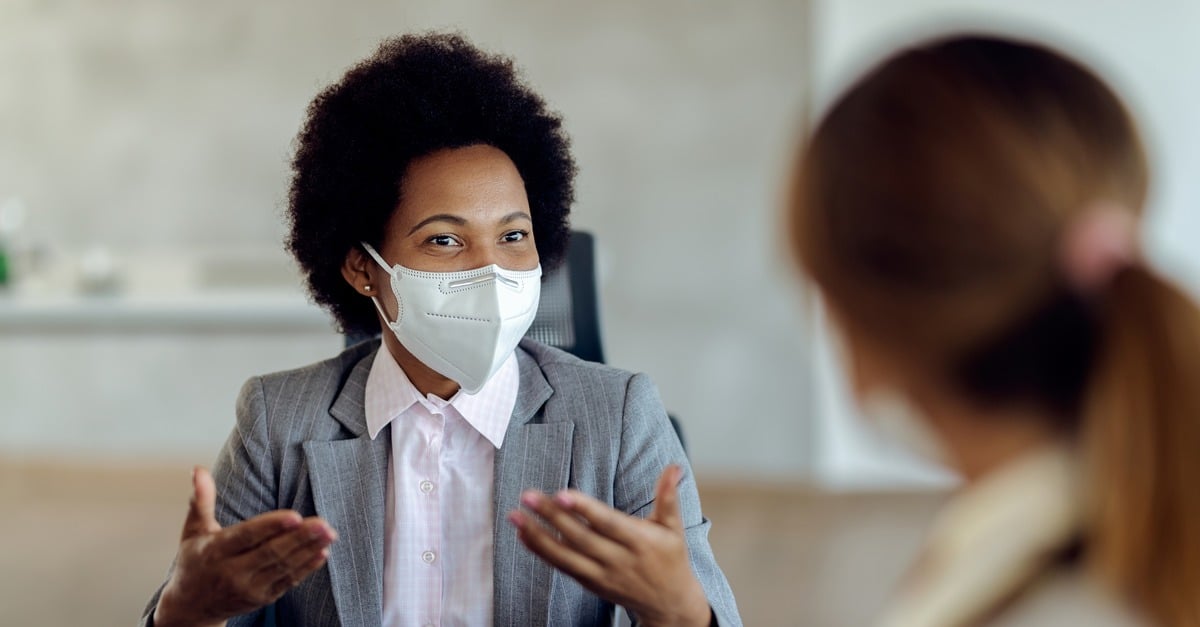 masked HR professional sits across from interviewee
